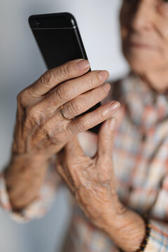 Hands of an elderly person using a smartphone. Technology concept.