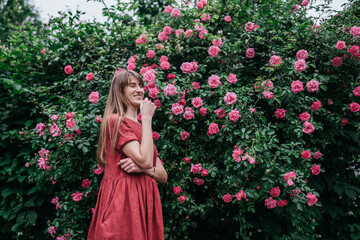 woman in red dress in the park with roses and flowers