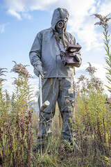 A military man in a chemical protection suit measures radiation with a dosimeter