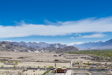 Beautiful landscape with fields, Tibetian buildings, snow mountains, and blue sky,  in Ladakh, Kashmir, view from Thiksey Monastery or Thiksey Gompa