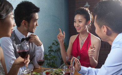 Four people sit together for dinner and chat 