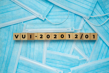 Text new variant coronavirus 19 on a wooden cube with a bundle of the medical face mask.