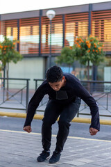 Active Latino young man jumping in action. Extreme sport activity, parkour outdoor free running or healthy lifestyle concept