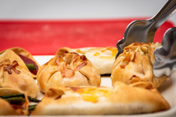 Horizontal macro view of canapés and sachets with vegetables and ham and a few waiter's tongs. New...