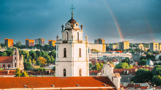 Vilnius, Lithuania. Sunset Cityscape Of Vilnius, Lithuania In Summer. Beautiful View Of Old Town In Evening. Sts Johns' Church Sv. Jonu baznycia . Altered Sky With Rainbow