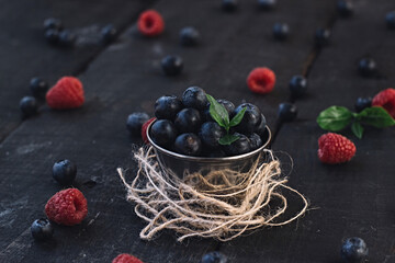 Berries colorful assorted mix blueberry and raspberry and sweet cherry on an old wooden table in a bowl.