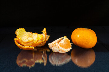 Segments of the tangerine on glass table with reflection