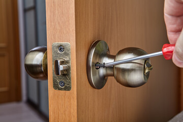 Mounting brass doorknob with exposed set-screw, close-up.
