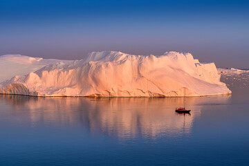 Greenland Ilulissat color glaciers at polar night with red sailing boat