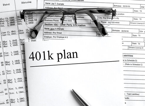 Paper with text 401k plan on a financial table with eyeglasses and metal pen