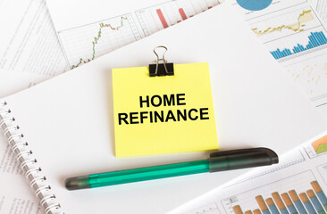 A yellow sticker with text Home Refinance is in a Notepad with a green pen financial charts and documents