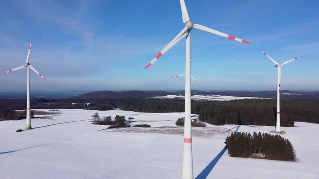 Bottom up aerial view of a wind farm. Aerial shot of rotating wind power plants in a winter landscape.