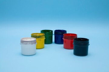 Plastic jars with multicolored paints on a blue background. Several colours of gouache, acrylic...