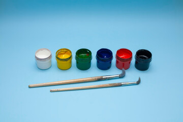 Plastic jars with multicolored paints on a blue background. Several colours of gouache, acrylic...