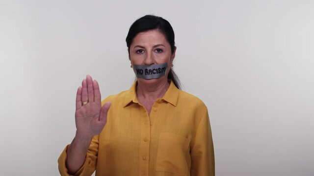 Old woman with mouth taped writing no racism.Old woman with tape in her mouth with no message to racism on white background. Message given silently. No racism.