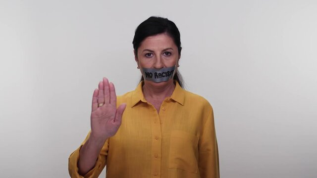 Old woman with mouth taped writing no racism.Old woman with tape in her mouth with no message to racism on white background. Message given silently. No racism.