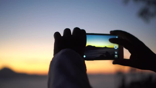 Hands traveler people taking apps pictures photo mountain landscape view with smartphone during sunrise golden hour. Traveling vacation and summer Relaxing of freedom with technology around world. 4k