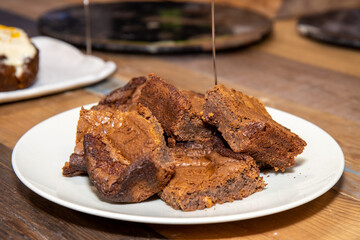 A plate of delicious chocolate brownies on a wooden kitchen work top, tasty deserts in a pile ready to be eaten