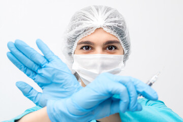 Portrait of female doctor in protective clothing,gloves and mask holding a syringe and showing forbidding gesture with her hands.Medicine and healthcare concept.Vaccination against coronavirus concept
