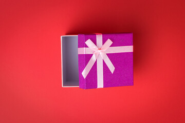 Slightly opened gift box on a red background.