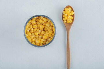 A wooden spoon full of popcorn seeds on a white background