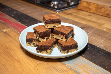 A plate of delicious chocolate brownies on a wooden kitchen work top, tasty deserts in a pile ready to be eaten