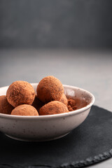 Date candy balls in a plate with carob on a slate Board close-up