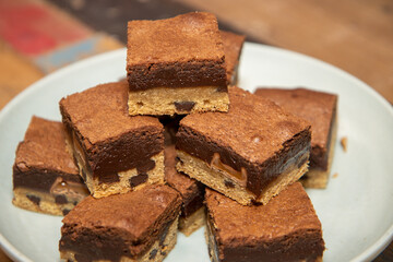 A plate of delicious chocolate brownies on a wooden kitchen work top, tasty deserts in a pile ready to be eaten