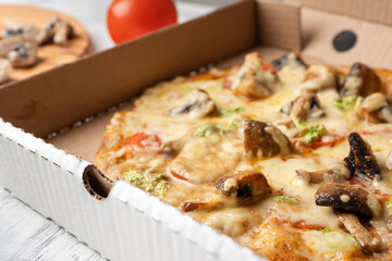 Vegetarian pizza with mushrooms near the ingredients in a cardboard box, close-up