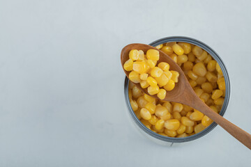 A wooden spoon full of popcorn seeds on a white background