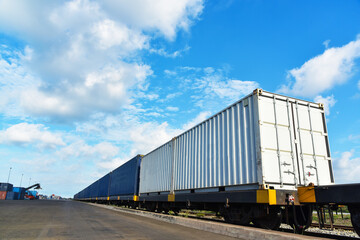 Cargo train platform with freight train Containers on the train on crane loading in port background.