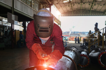 Welder mounts in the trunk pipeline electrochemical  piping shop in shipyard by wearing protection...