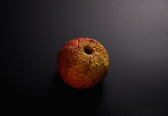 a wrinkled apple in a ray of light on a dark background