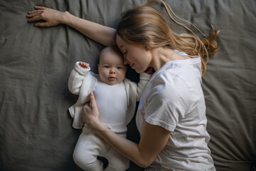Happy woman looks at her baby and smiles. Beautiful baby smiles at mother. Mother with her own baby.