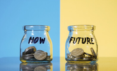 Budget and saving concept. Two money jars labeled with words now and future.