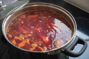 A boiling pot of traditional sour Borscht soup,  one of the most famous dishes of Ukrainian cuisine, made with beetroots as one of the main ingredients, which give the dish its distinctive red color