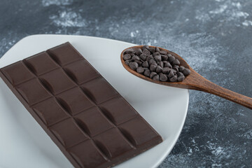 Bar of chocolate with chocolate chips on a marble background