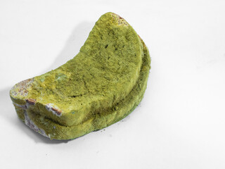 A piece of bread covered with green mold on a white background isolate