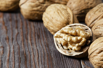 Walnuts on a dark brown wooden background. Close up. Selective focus, side view. Copy space.