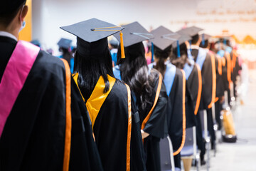 Rearview of the university graduates line up for degree award in university graduation ceremony. The university graduates are gathering in the university graduation ceremony. Crowd of the graduates.