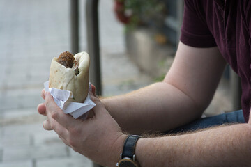 Man holding a Pita bread with Falafel, a typical middle eastern food, deep fried balls made of ground chickpeas. Tel Aviv, Israel