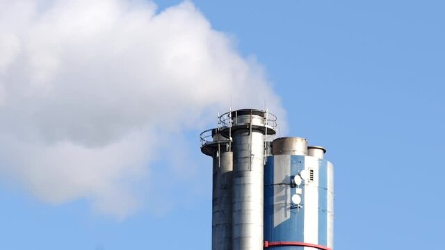 Close up of industrial chimney with emission, with a clear blue sky