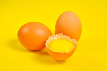 Chicken eggs on a yellow background broken with yolk.