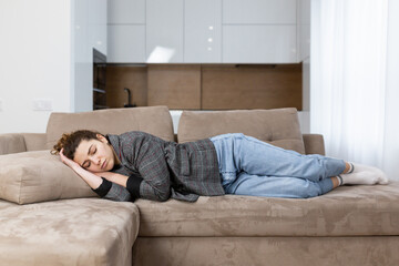 Exhausted young student or business woman on the couch after work. Sleepy without strength Adult girl after a hard day's work goes to bed at home on the sofa.