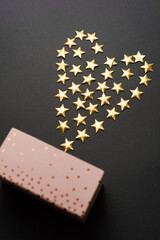 Nice photo of a gift and above it some little stars shaped in a heart .