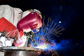 iIndustry welding worker with a metal piping in factory with spark light by Mig wear equipment...