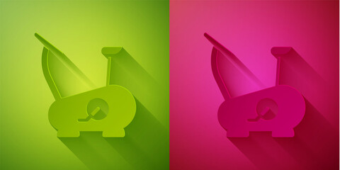 Paper cut Stationary bicycle icon isolated on green and pink background. Exercise bike. Paper art style. Vector.
