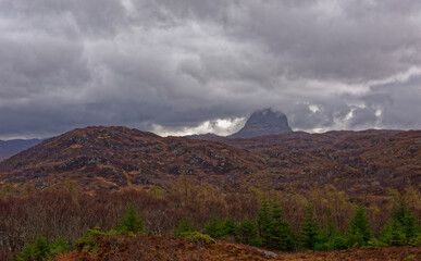 Suilven seen from the top of Cloug Wood Nature Reserve near to Lochinver, with low dark clouds covering the summit of Meall Meadhonach.