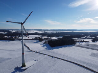 Aerial view of a wind farm in a winter landscape during sunset. Aerial view of wind turbines during sunset.