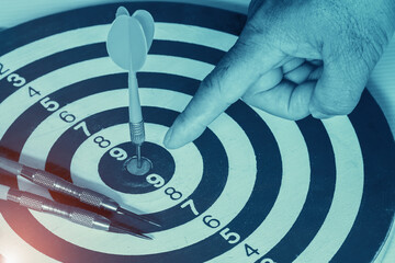 Dart arrow hitting in the target center of dartboard and pointing hand Target business, achieve and...
